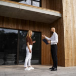 Photo d'une femme et d'un homme faisant affaire devant un bâtiment en bois.