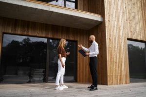 Photo d'une femme et d'un homme faisant affaire devant un bâtiment en bois.